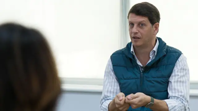 Foto de Ricardo Salles, vestindo uma camisa azul listrada e um colete azul por cima. 